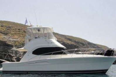 White luxury yacht anchored near rocky coastline under a clear sky.